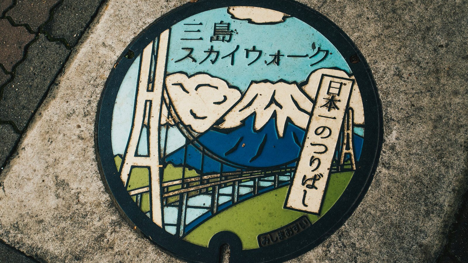 Japanese manhole cover with bridge and mountain art