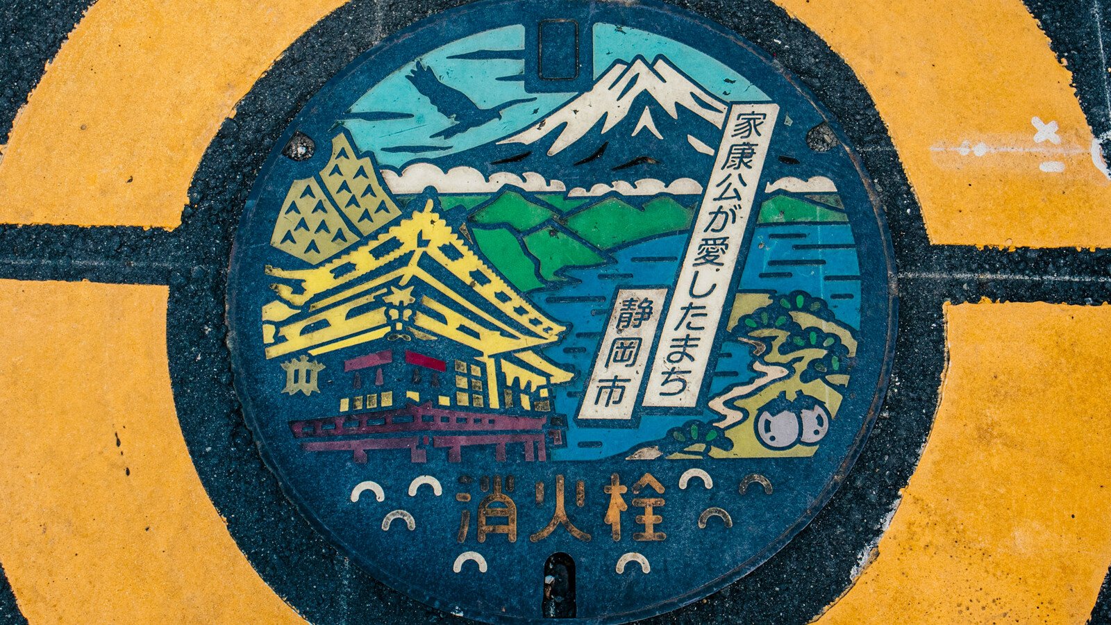 Japanese manhole cover with traditional building and mountain 