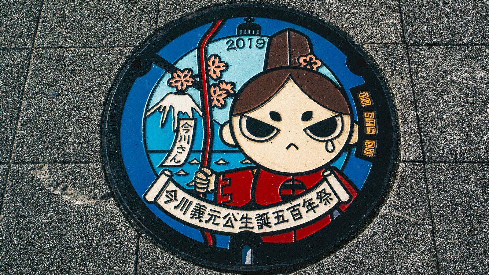 Japanese manhole cover with cartoon traditional woman art