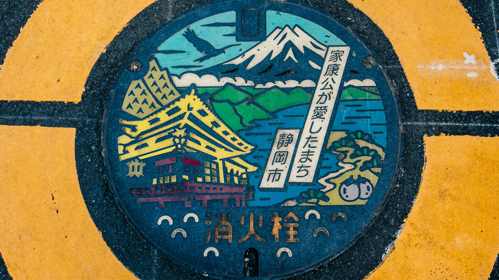 Japanese manhole cover with traditional building and mountain