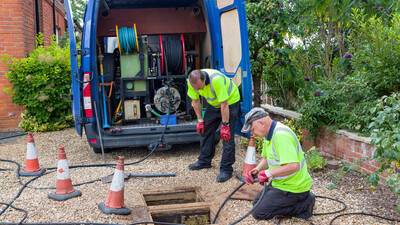 Drainage jetting team with manhole open and rodding equipment to unblock drains