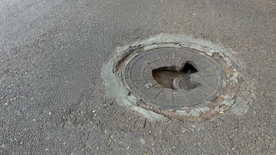 broken manhole cover smashed in road